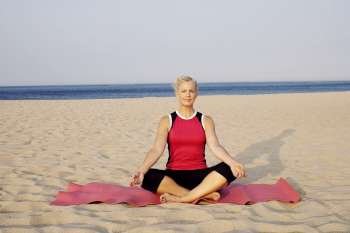 Portrait of a mature woman performing yoga on the beach