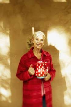 Senior woman holding a teapot and smiling