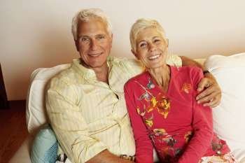 Portrait of a mature man and a senior woman sitting on a couch and smiling
