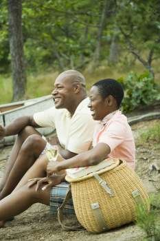 Side profile of a couple sitting near a picnic basket and smiling