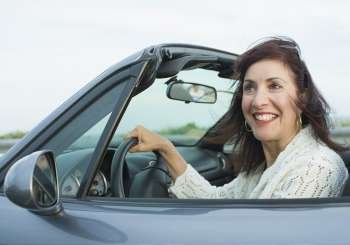 Mature woman sitting in a car and smiling