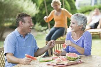 Mature couple eating watermelon slices in a lawn