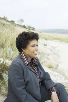 Mature woman sitting on the beach and smiling