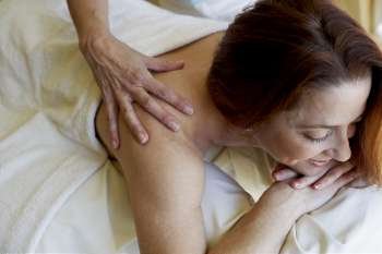 Close-up of a mid adult woman getting a shoulder massage from a massage therapist
