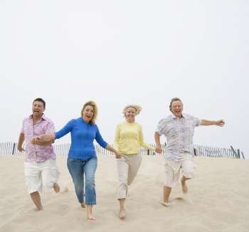 Two couples running on the beach with holding their hands