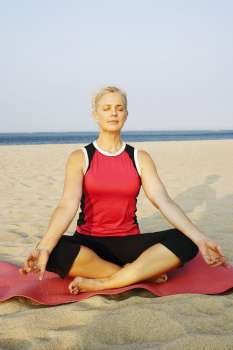 Mature woman performing yoga on the beach
