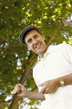 Low angle view of a mature man holding a golf club and a golf ball