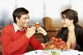 Mid adult couple sitting in a restaurant and toasting with wine glasses