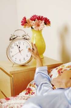 Close-up of a woman reaching for an alarm clock