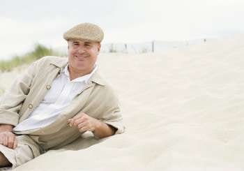 Portrait of a mature man reclining on the beach and smiling
