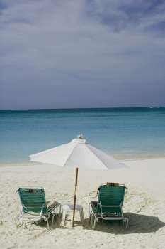 Two empty chairs and a beach umbrella on the beach