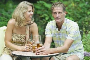 Mature couple sitting at a table and holding glasses of ice tea