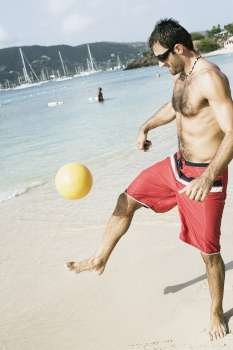 Mid adult man playing beach volleyball on the beach