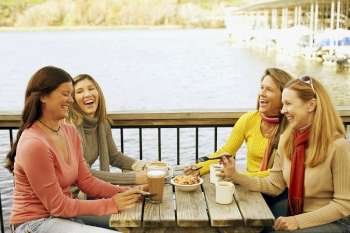 Four mature women sitting at a sidewalk cafe and laughing