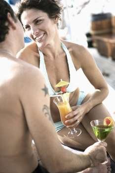 Mid adult couple holding glasses of cocktail and looking at each other