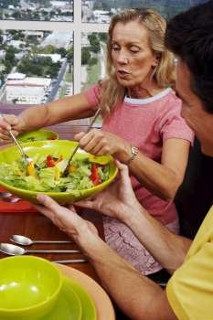 Mature woman taking salad from a bowl
