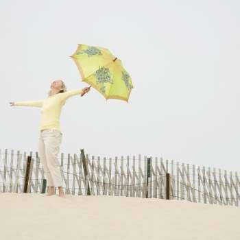 Side profile of a mid adult woman holding an umbrella with her arms outstretched