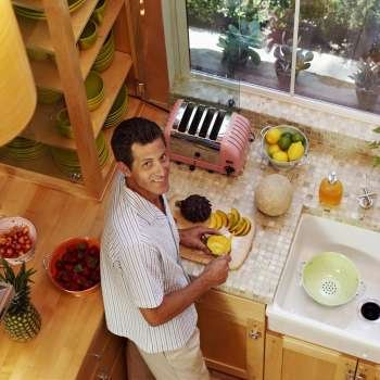 Portrait of a mature man cutting fruits in a kitchen