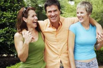 Mature man and two mature women standing together and smiling