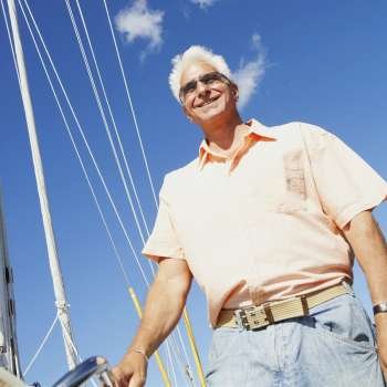 Low angle view of a mature man standing in a sailboat and smiling