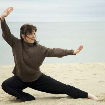 Mature woman practicing martial arts on the beach