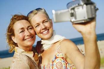 Close-up of two mature women taking a picture of themselves on the beach