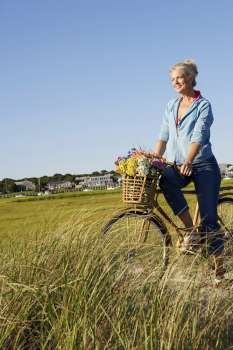 Mature woman standing in the field with a bicycle