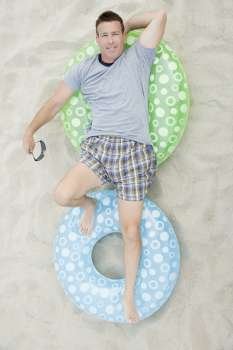 High angle view of a mature man lying on inflatable rings