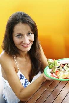 Portrait of a mid adult woman holding a plate of food