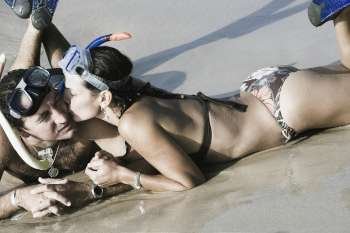 Mid adult woman kissing to a mid adult man on the beach
