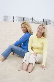 Mid adult woman and a mature woman sitting on the beach
