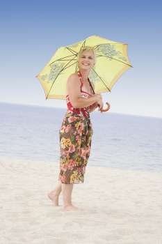 Side profile of a mature woman holding an umbrella on the beach