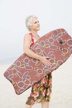 Side profile of a mature woman carrying a body board