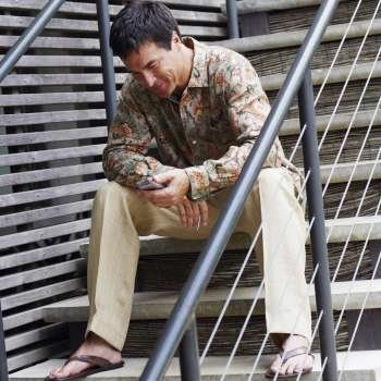 Mature man sitting on a staircase and holding a personal data assistant