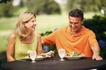 Mature couple sitting at the table with plates of salad in front of them