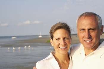 Portrait of a mature couple standing on the beach and smiling