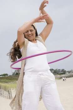 Mature woman playing with a plastic hoop on the beach