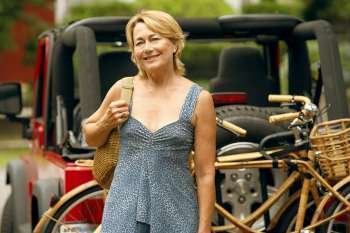 Portrait of a mature woman smiling with a sports utility vehicle and bicycles in the background