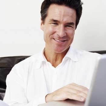 Close-up of a mature man using a laptop and smiling