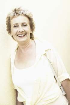 Portrait of a mature woman leaning against a wall and smiling