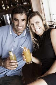 Portrait of a mid adult couple holding glasses of juice and smiling