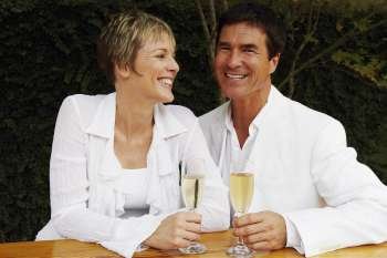 Mature couple holding cups in the kitchen and smiling