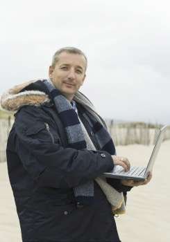 Portrait of a mature man using a laptop on the beach