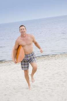 Portrait of a mature man walking with a surfboard on the beach and smiling