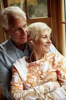 Close-up of a senior woman wearing headphones and smiling with a mature man