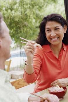 Close-up of a mature woman feeding a mature man with chopsticks