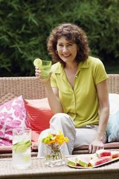 Portrait of a mature woman sitting on a couch and holding a glass of lemonade