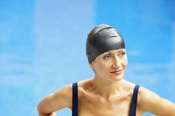 Close-up of a mid adult woman standing near a swimming pool and looking away