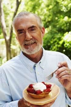 Portrait of a mature man eating tart with a fork