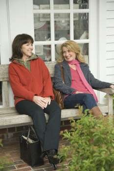 Two mature women sitting on a bench and gossiping